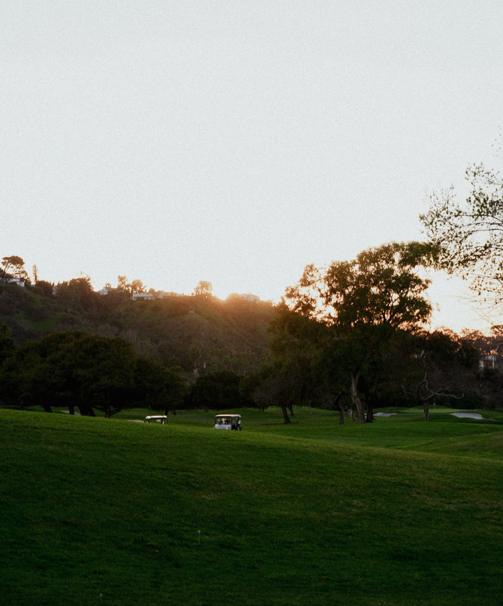 Sunset on a golf course with a golf cart in the background.