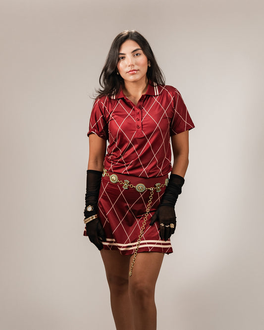 A model wearing the Sicilia Polo - Maroon, showcasing a maroon polo shirt with a diamond pattern, paired with a matching Sicilia skirt. The outfit exudes elegance and comfort, perfect for golf or casual wear.